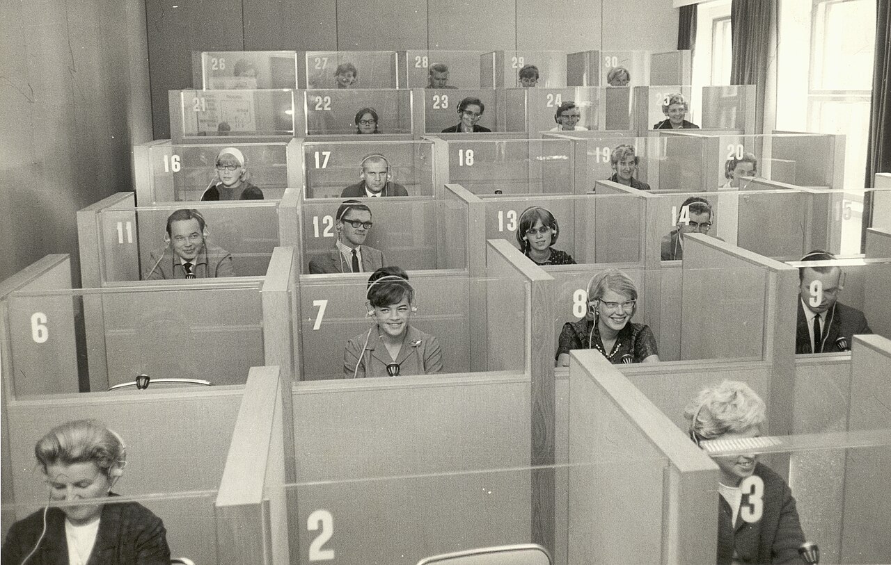 Studierende mit Kopfhörern in einem Sprachlabor der 1960er Jahre — in solchen Hörkabinen nahm die frühe Shadowing-Forschung beim Sprachenlernen ihren Anfang